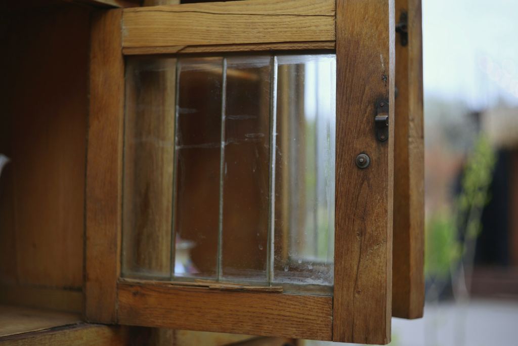 Geöffneter alter Holzfensterflügel mit drei Glasscheiben, das Holz verwittert und warmbraun.