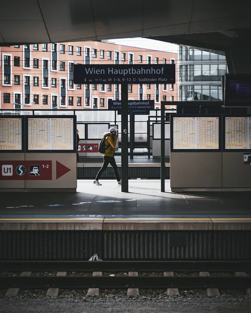 Bahnsteig am Wiener Hauptbahnhof, eine Person in gelber Jacke geht Richtung Ausgang.